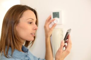 Pro Woman Regulating Thermostat With Smartphone Shutterstock 140835070